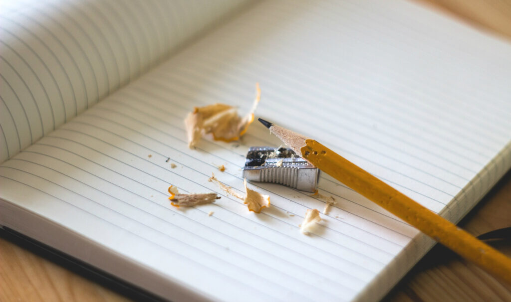 Penna och pennvässare ligger på en skrivbok