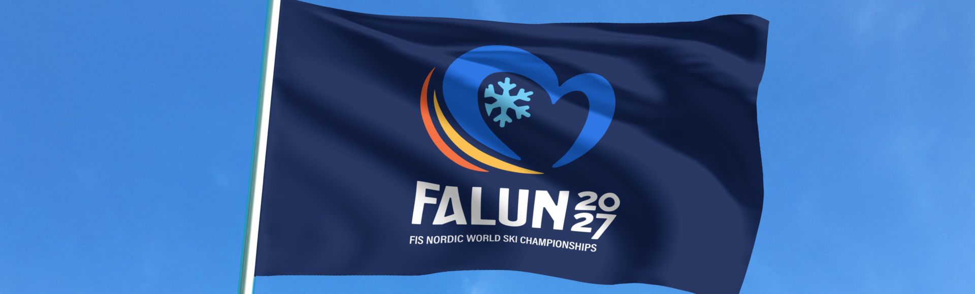 En flagga med logotypen för skid-vm 2027 i Falun syns mot en blå himmel.