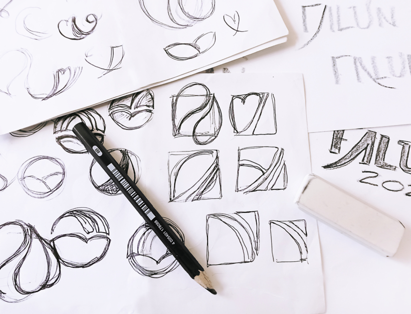 En blyertspenna samt skisser på ett papper visa skissarbetet vid framtagningen av Skid-VMs logotyp